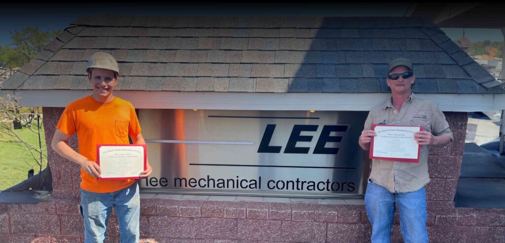 Image of Lee Mechanical employees standing in front of sign holding certificates